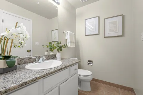 a bathroom with a granite countertop sink a toilet and a mirror