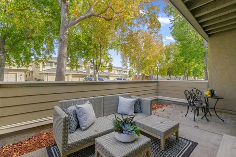 a view of a patio with couches and table and chairs with wooden floor and fence