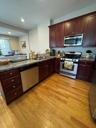a kitchen with stainless steel appliances granite countertop wooden cabinets a stove top oven with a sink and dishwasher