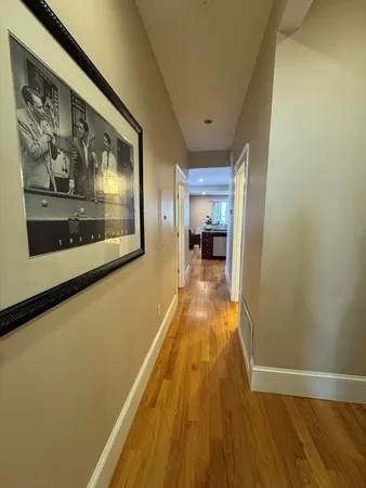 a view of a hallway with wooden floor and a flat screen tv