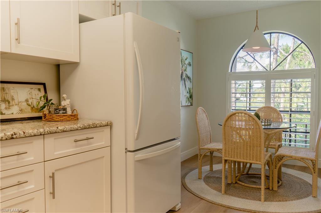 265 Deerwood Circle, Unit 10 Naples, FL 34113 - Photo 15 of 38 Kitchen featuring light wood-type flooring, light stone counters, freestanding refrigerator, and white cabinetry