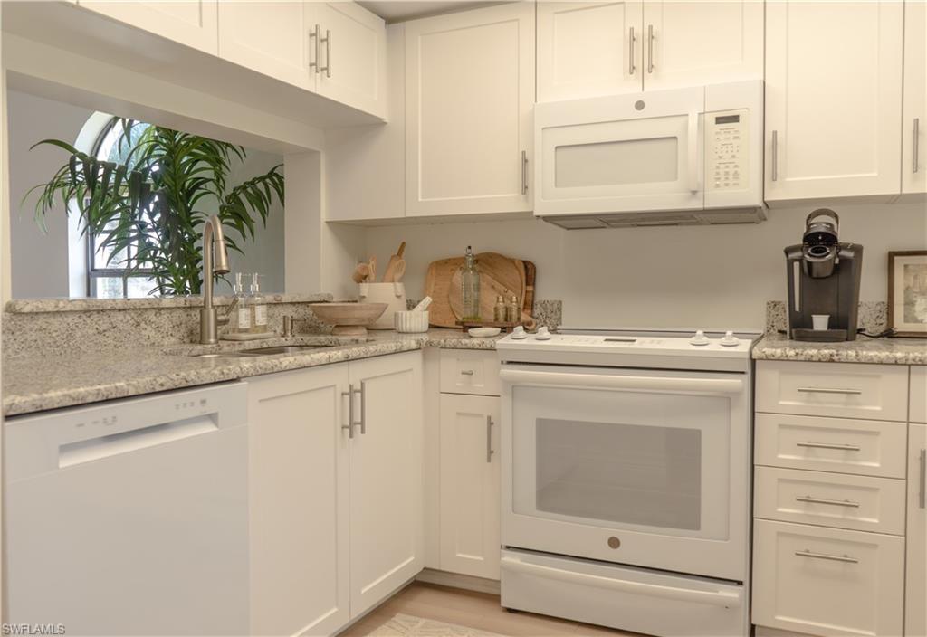 265 Deerwood Circle, Unit 10 Naples, FL 34113 - Photo 16 of 38 Kitchen featuring white cabinets, a sink, white appliances, light wood-style floors, and light stone countertops