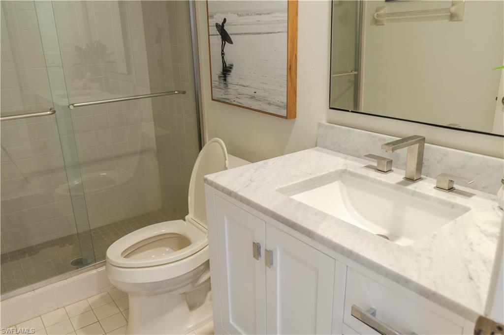 265 Deerwood Circle, Unit 10 Naples, FL 34113 - Photo 26 of 38 Bathroom with toilet, a shower stall, tile patterned flooring, and vanity