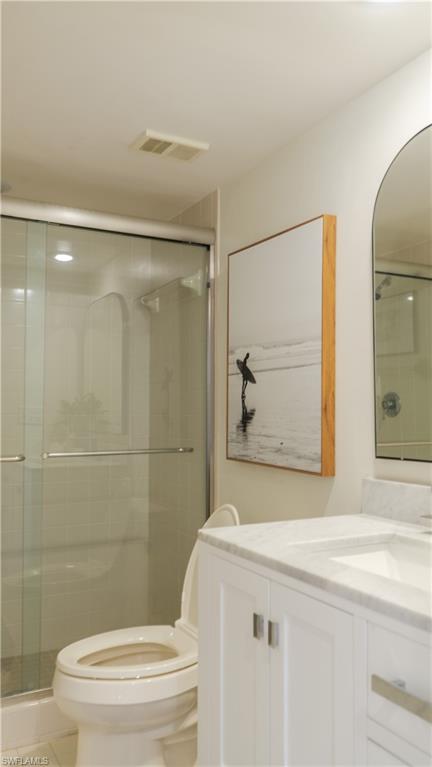 265 Deerwood Circle, Unit 10 Naples, FL 34113 - Photo 27 of 38 Bathroom with visible vents, toilet, a shower stall, and vanity