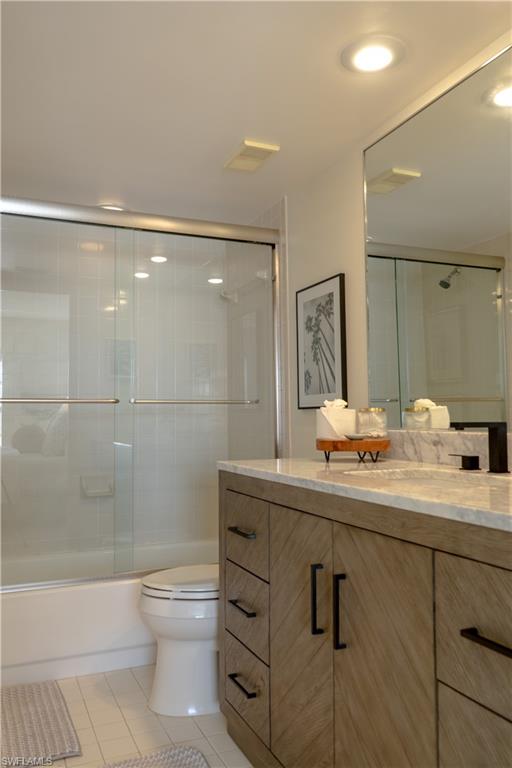 265 Deerwood Circle, Unit 10 Naples, FL 34113 - Photo 36 of 38 Bathroom with visible vents, bath / shower combo with glass door, toilet, vanity, and tile patterned floors