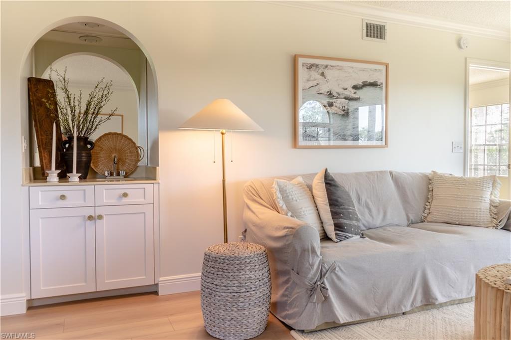 265 Deerwood Circle, Unit 10 Naples, FL 34113 - Photo 6 of 38 Living area with light wood-style floors, crown molding, visible vents, and arched walkways