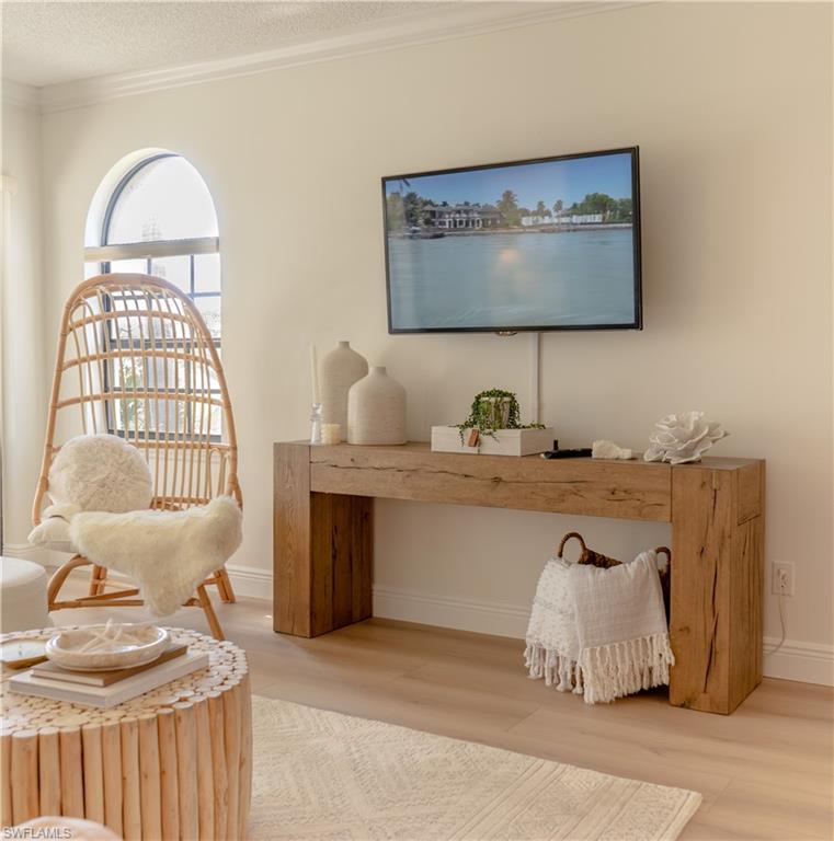 265 Deerwood Circle, Unit 10 Naples, FL 34113 - Photo 7 of 38 Living area with ornamental molding, wood finished floors, and a textured ceiling