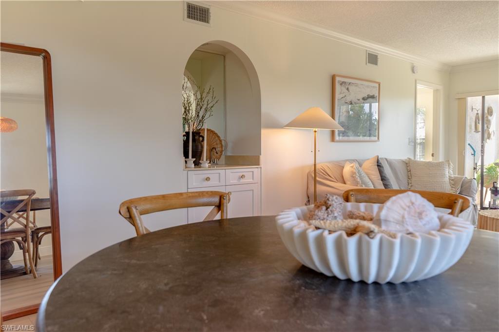 265 Deerwood Circle, Unit 10 Naples, FL 34113 - Photo 8 of 38 Dining room featuring crown molding, visible vents, and a textured ceiling