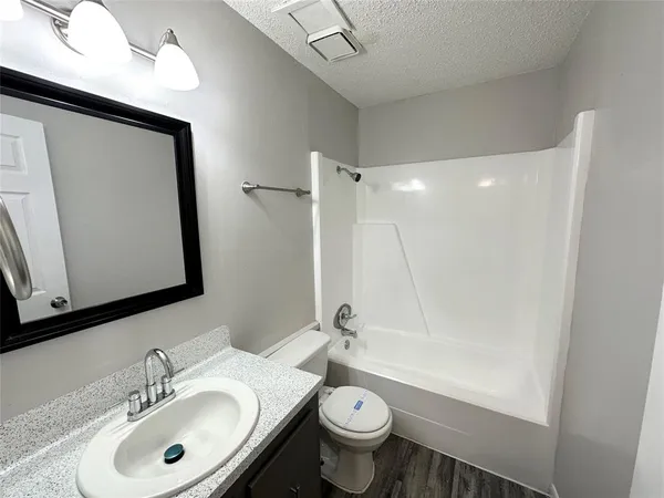a bathroom with a sink a toilet and shower a mirror