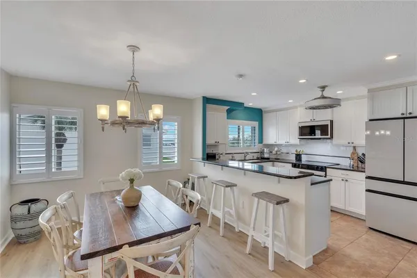 a kitchen with stainless steel appliances granite countertop a sink dishwasher a stove a refrigerator a dining table and chairs with wooden floor