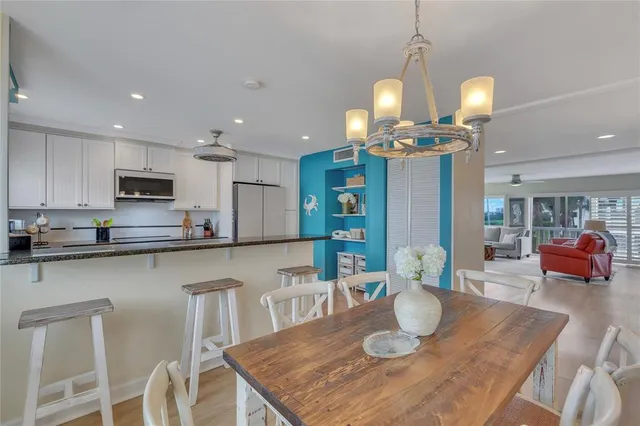 a kitchen with stainless steel appliances granite countertop a sink a refrigerator and chairs