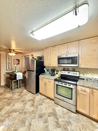 a kitchen with stainless steel appliances granite countertop a stove top oven a sink a dining table and chairs with wooden floor
