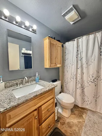 a bathroom with a granite countertop sink a toilet and a mirror