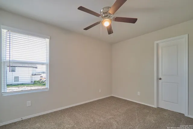 an empty room with windows and fan