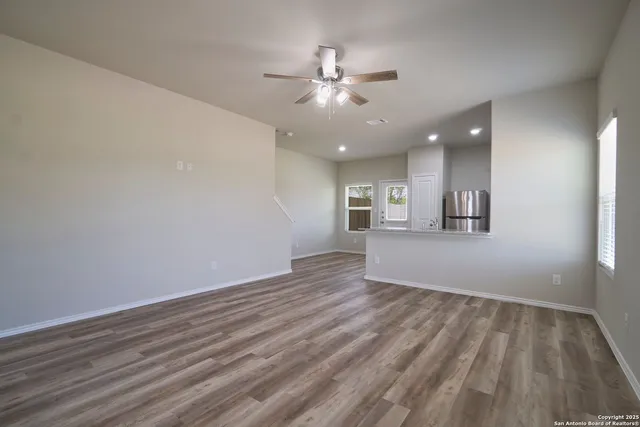 wooden floor in an empty room with a chandelier fan