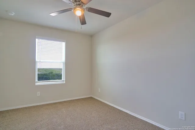 an empty room with a window and a fan
