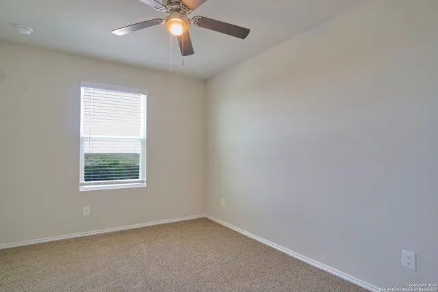 an empty room with a window and a fan