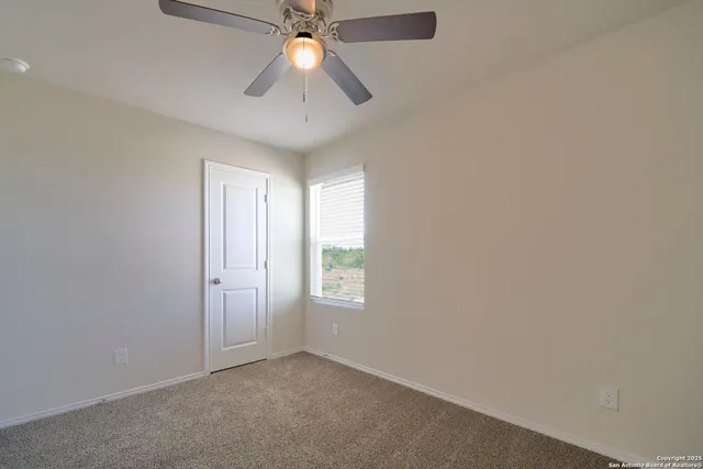 an empty room with a window and a fan