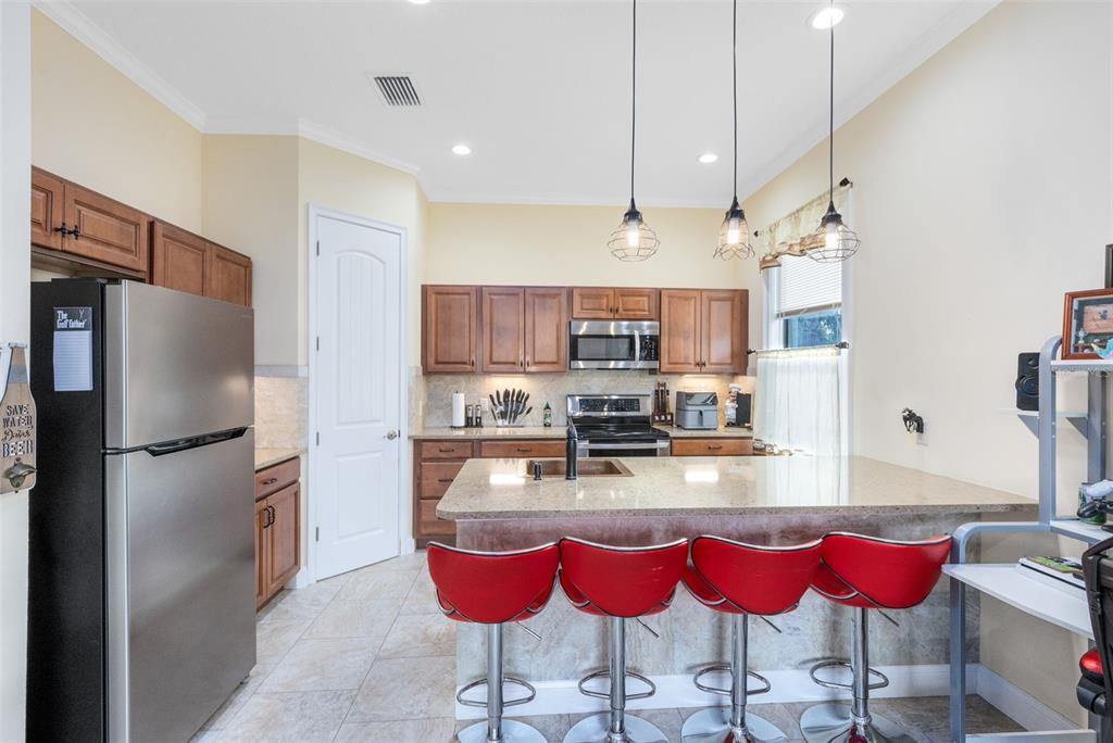 5300 Carson Street St. Cloud, FL 34771 - Photo 50 of 59 a kitchen with granite countertop a refrigerator a stove a kitchen island and chairs with wooden floor