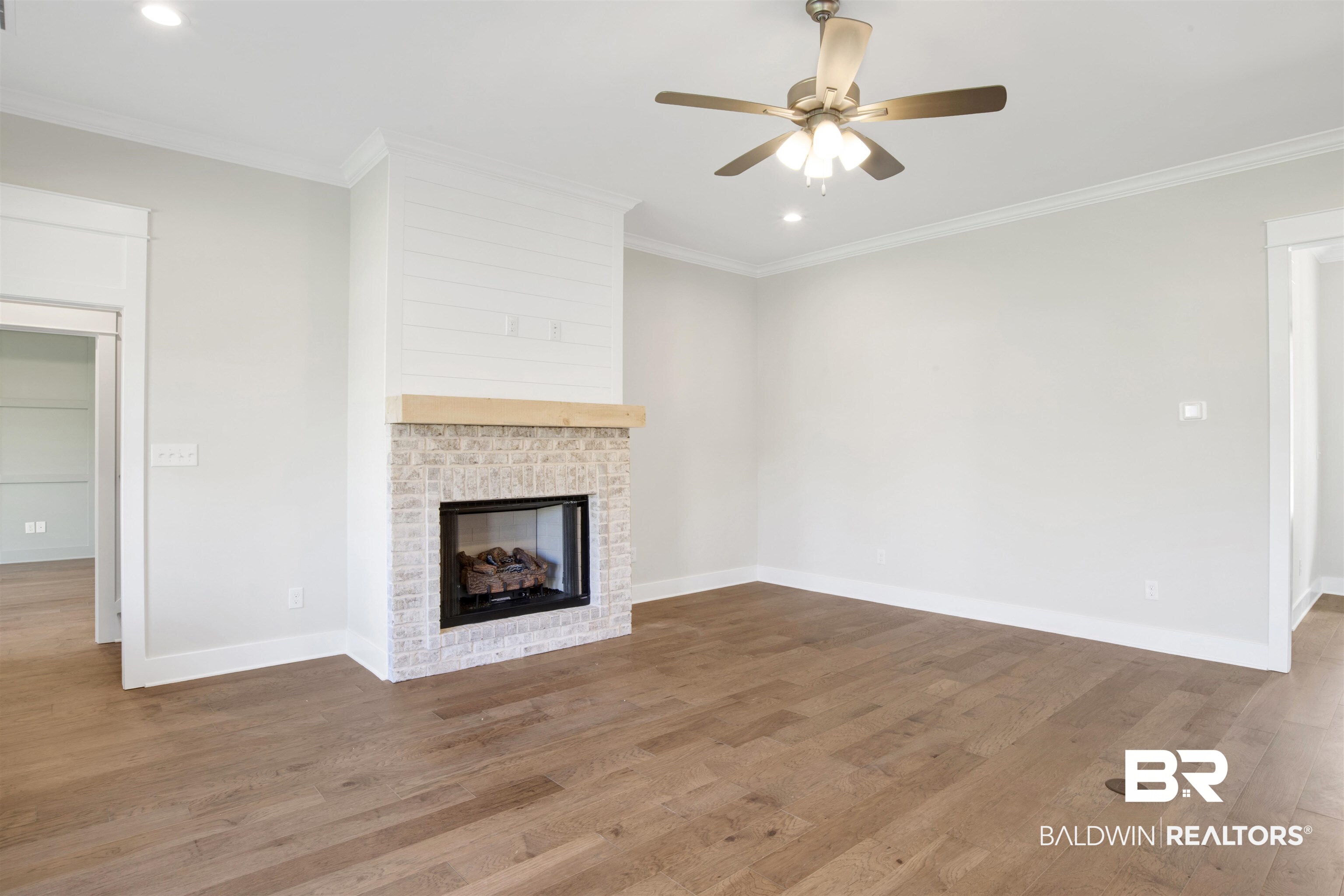 9687 Widgeon Court Daphne, AL 36526 - Photo 9 of 40 Unfurnished living room with hardwood / wood-style floors, a fireplace, ceiling fan, and crown molding