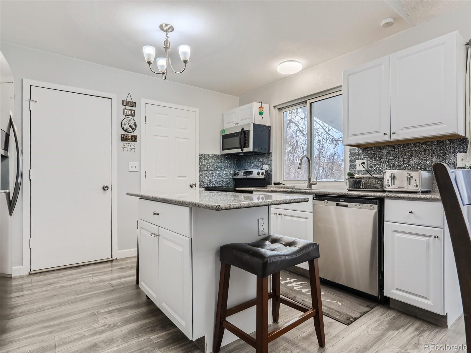 5941 South Perth Street Centennial, CO 80015 - Photo 9 of 28 a kitchen with a refrigerator a stove a microwave oven a sink and dishwasher with wooden floor