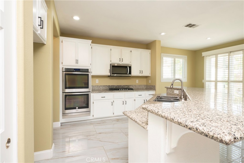 19128 Trail Ride Court Perris, CA 92570 - Photo 3 of 50 a kitchen with granite countertop white cabinets and stainless steel appliances