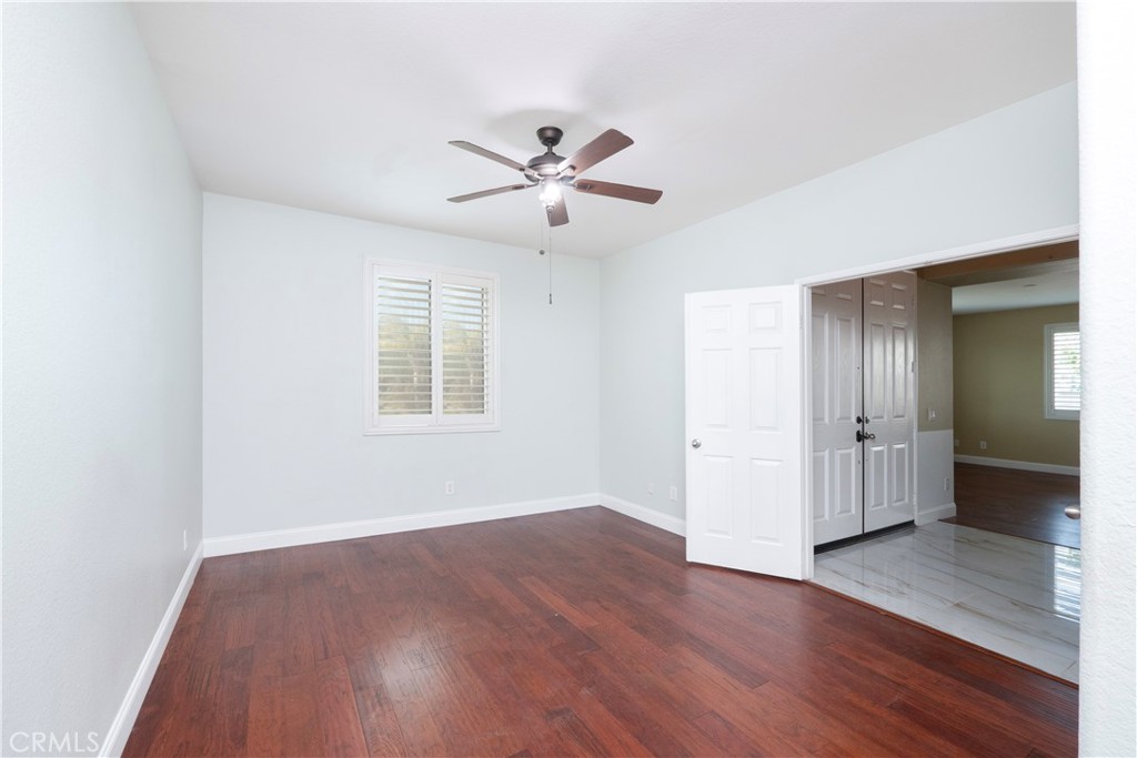 19128 Trail Ride Court Perris, CA 92570 - Photo 31 of 50 an empty room with wooden floor a ceiling fan and windows