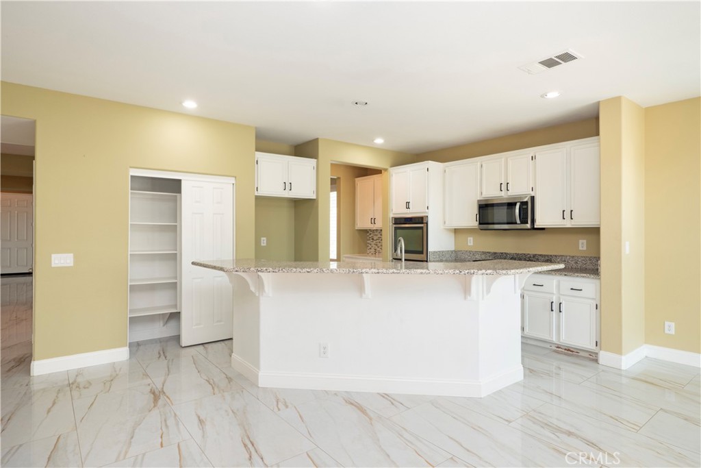 19128 Trail Ride Court Perris, CA 92570 - Photo 4 of 50 a large kitchen with stainless steel appliances granite countertop a refrigerator and a stove top oven