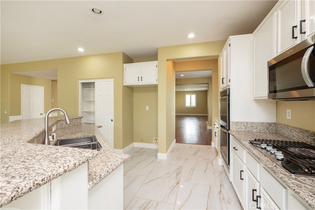 19128 Trail Ride Court Perris, CA 92570 - Photo 5 of 50 a kitchen with granite countertop a sink stainless steel appliances and cabinets