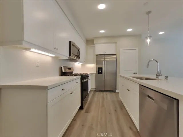 a kitchen with white cabinets sink and stainless steel appliances