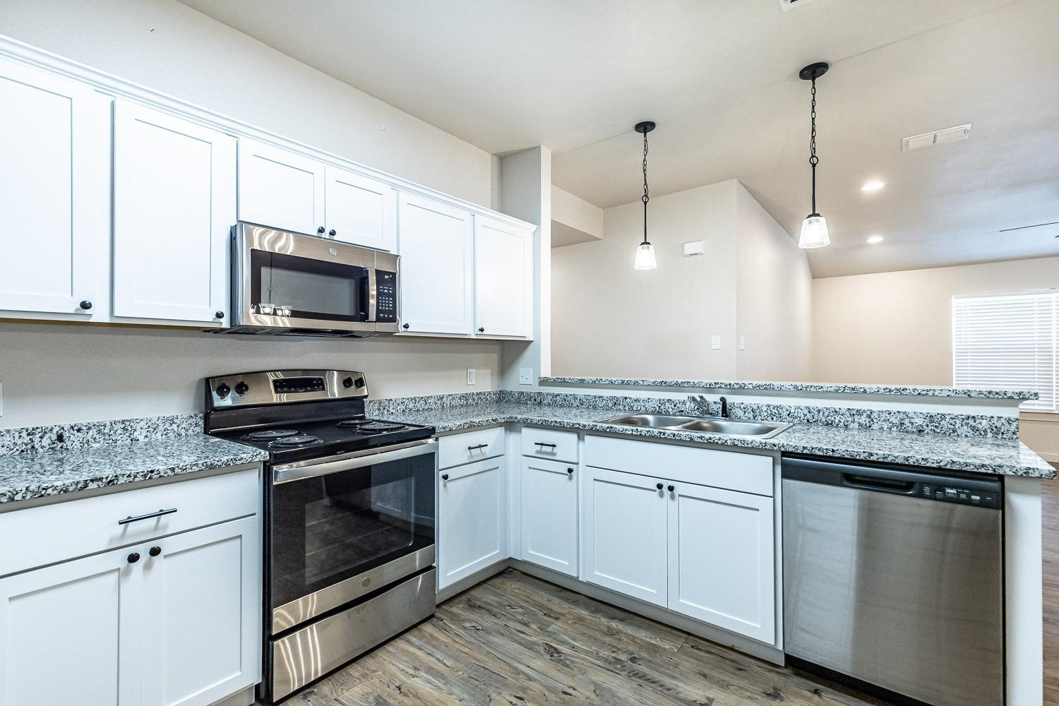 5517 121st Street, Unit B Lubbock, TX 79424 - Photo 20 of 37 a kitchen with stainless steel appliances granite countertop a stove a sink and a microwave
