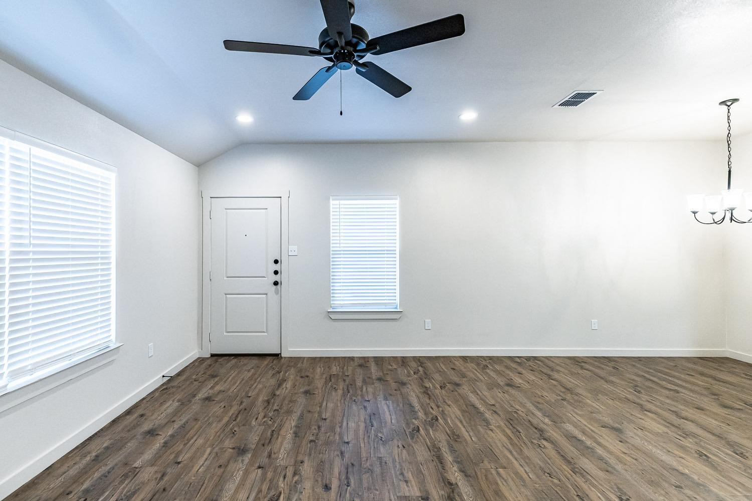 5517 121st Street, Unit B Lubbock, TX 79424 - Photo 9 of 37 an empty room with wooden floor fan and windows