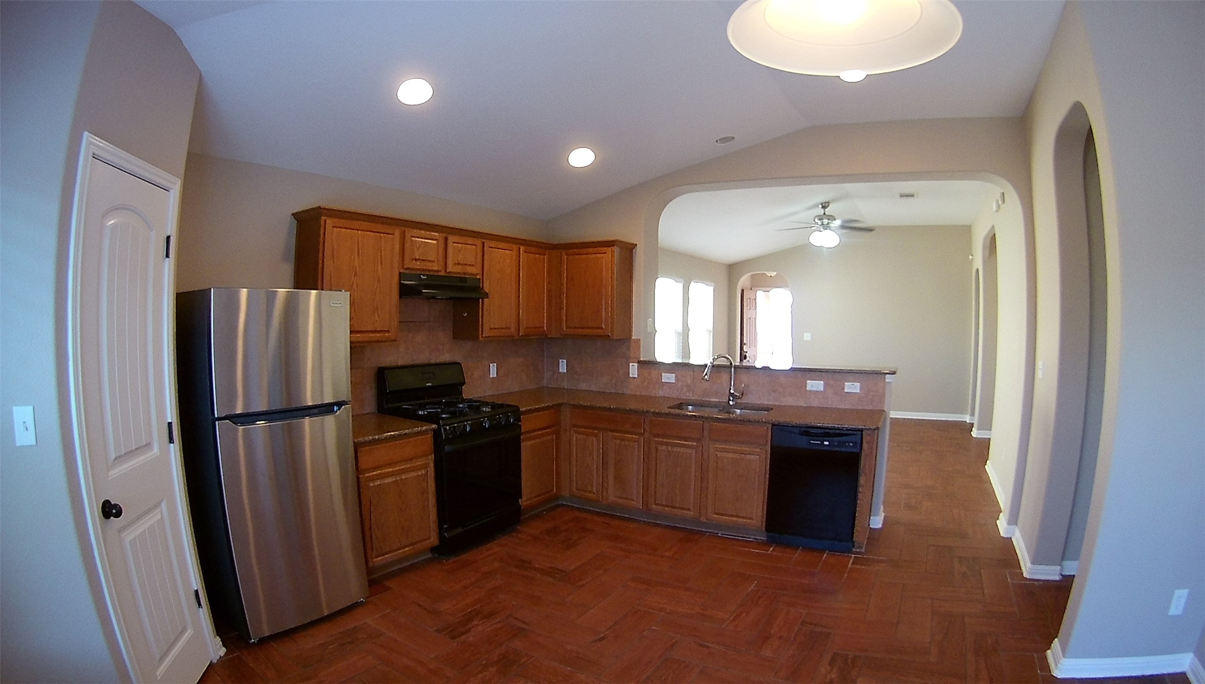3304 Wickham Lane Austin, TX 78725 - Photo 2 of 13 Kitchen featuring black appliances, vaulted ceiling, arched walkways, tasteful backsplash, and wood finish cabinets