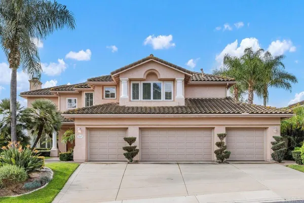 a front view of a house with a garden and palm trees