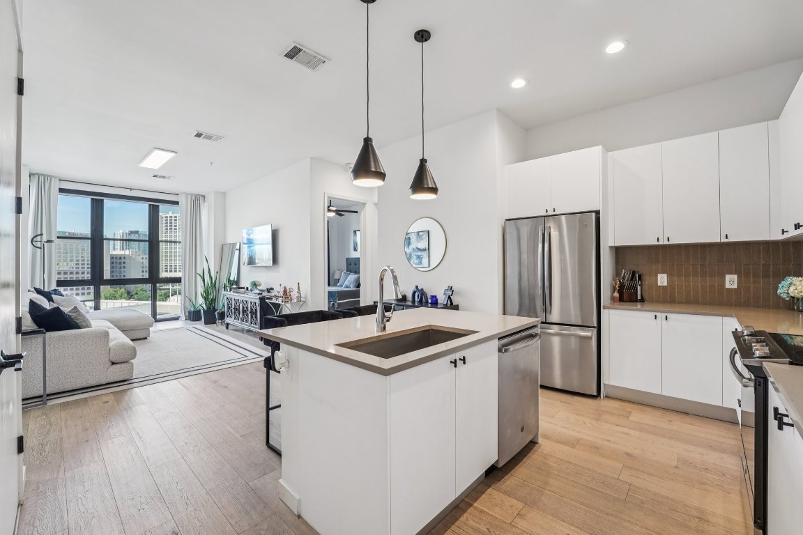 800 Embassy Drive, Unit 429 Austin, TX 78702 - Photo 12 of 40 a kitchen with stainless steel appliances granite countertop a sink a stove a refrigerator and island with wooden floor