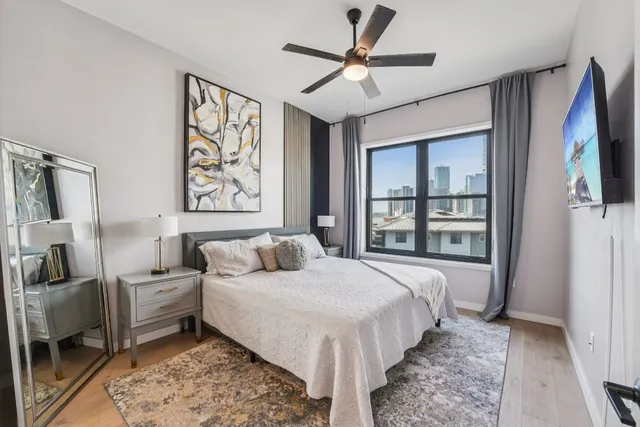 a spacious bedroom with a large bed a flat screen tv and a window