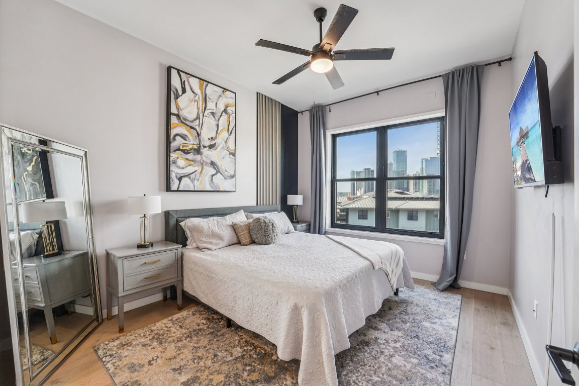 800 Embassy Drive, Unit 429 Austin, TX 78702 - Photo 14 of 40 a spacious bedroom with a large bed a flat screen tv and a window