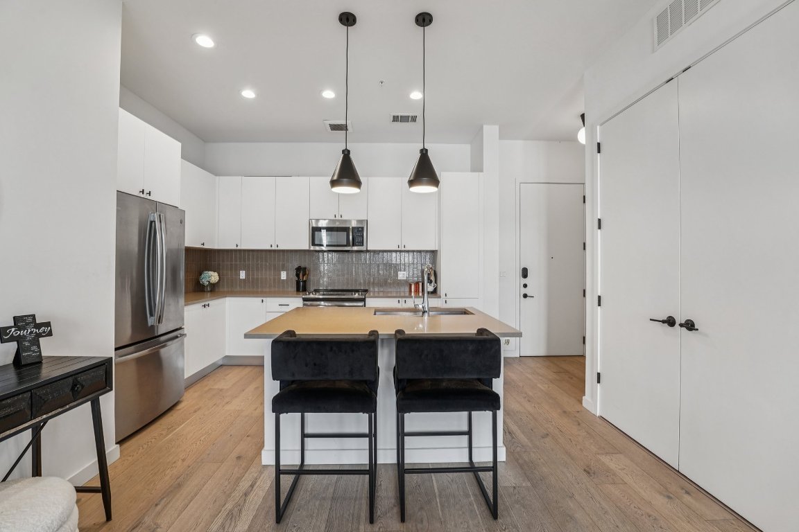 800 Embassy Drive, Unit 429 Austin, TX 78702 - Photo 10 of 40 a kitchen with stainless steel appliances a dining table chairs refrigerator and microwave