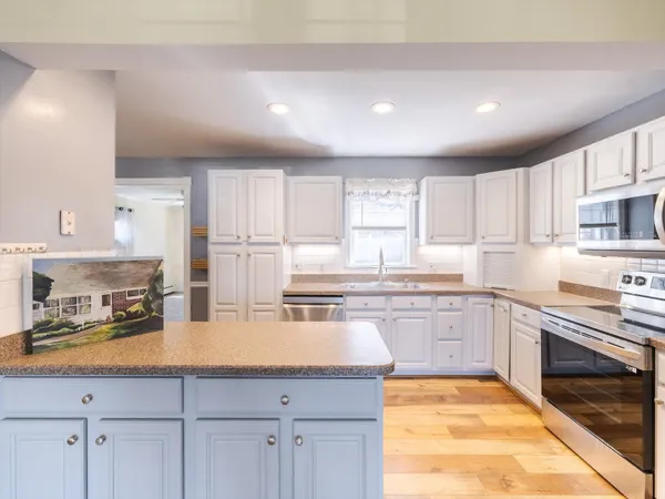 a kitchen with kitchen island granite countertop a stove sink and cabinets