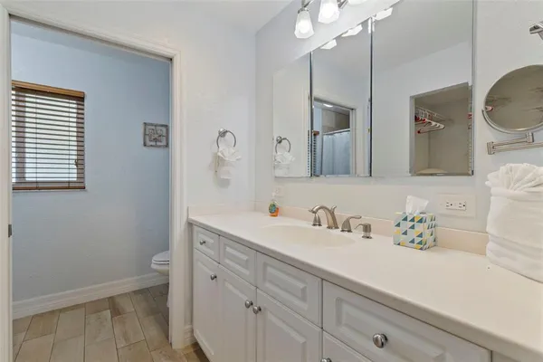 a bedroom with a bed a mirror on the dresser and a chandelier