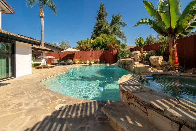 a backyard of a house with table and chairs plants and large trees