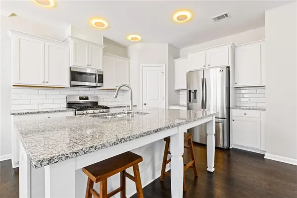 a kitchen with stainless steel appliances granite countertop a sink refrigerator and microwave