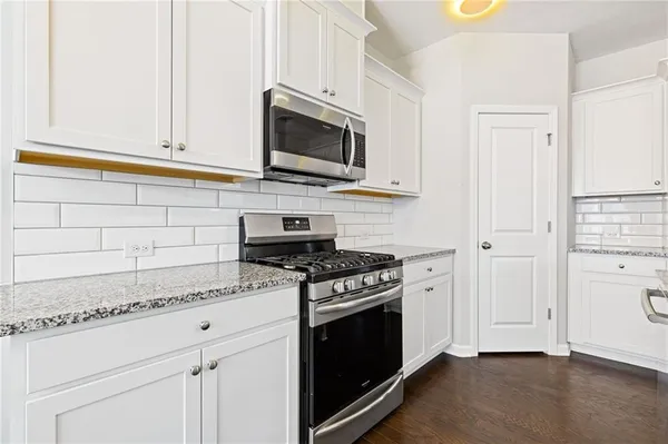 a kitchen with stainless steel appliances white cabinets and a stove top oven