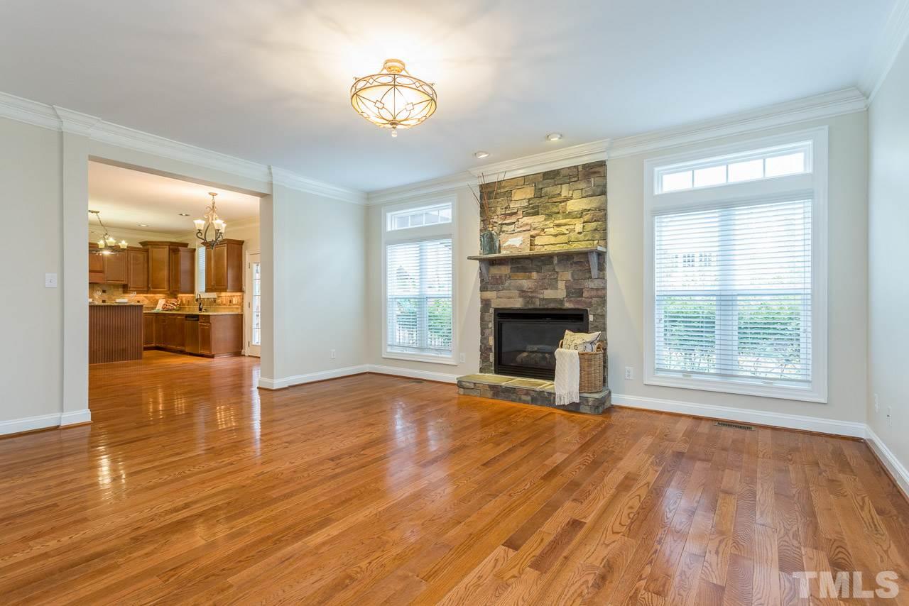 4208 Russling Leaf Lane Raleigh, NC 27613 - Photo 8 of 25 an empty room with wooden floor a fireplace and windows