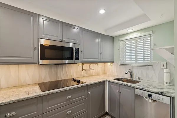 a kitchen with granite countertop cabinets stainless steel appliances a sink and a window