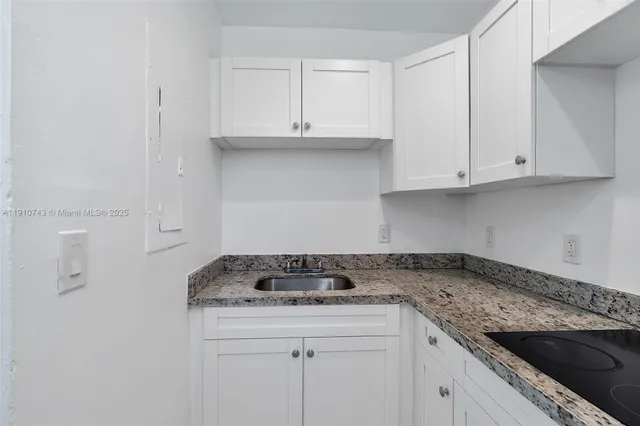 a kitchen with granite countertop white cabinets and a stove