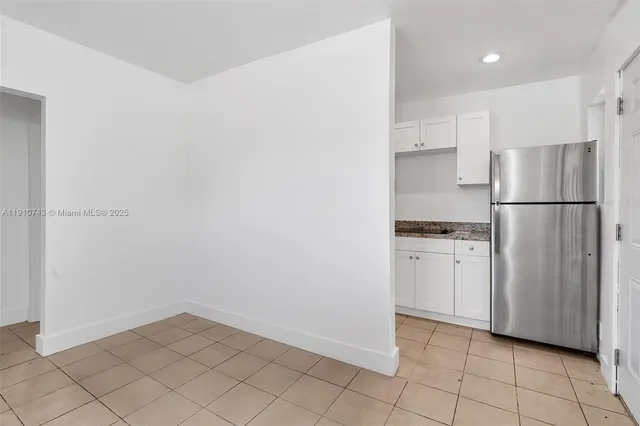 a kitchen with white cabinets and refrigerator