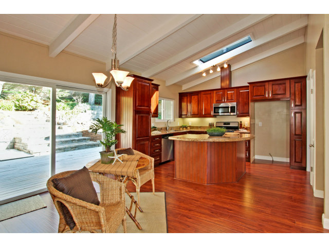 457 Monterey Drive Aptos, CA 95003 - Photo 7 of 11 a kitchen with stainless steel appliances kitchen island granite countertop a refrigerator a sink a dining table and chairs with wooden floor
