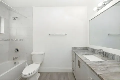 a bathroom with a granite countertop sink a toilet and shower