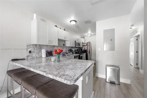 a kitchen with stainless steel appliances granite countertop a sink dishwasher and refrigerator with wooden floor